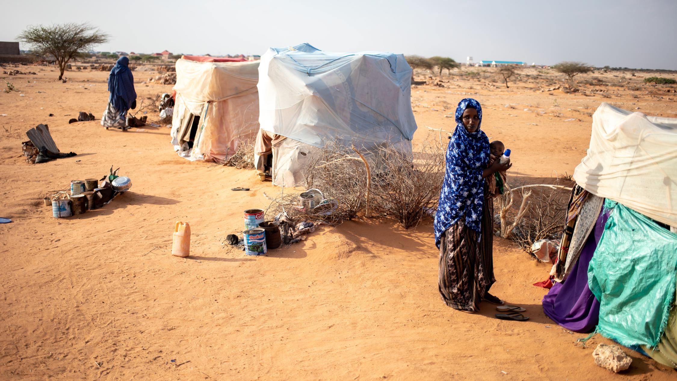 Frauen stehen vor provisorisch aufgebauten Zelten in einer Dürre-Landschaft in Somalie